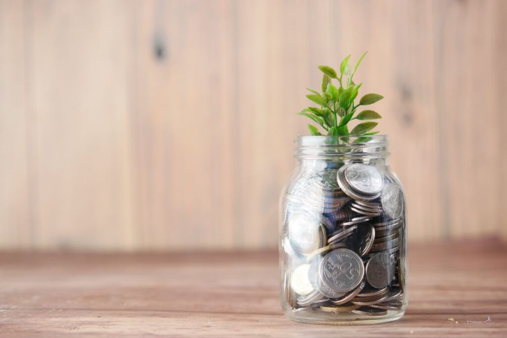 Frasco lleno de monedas con una planta creciendo, simbolo del ahorro para el retiro