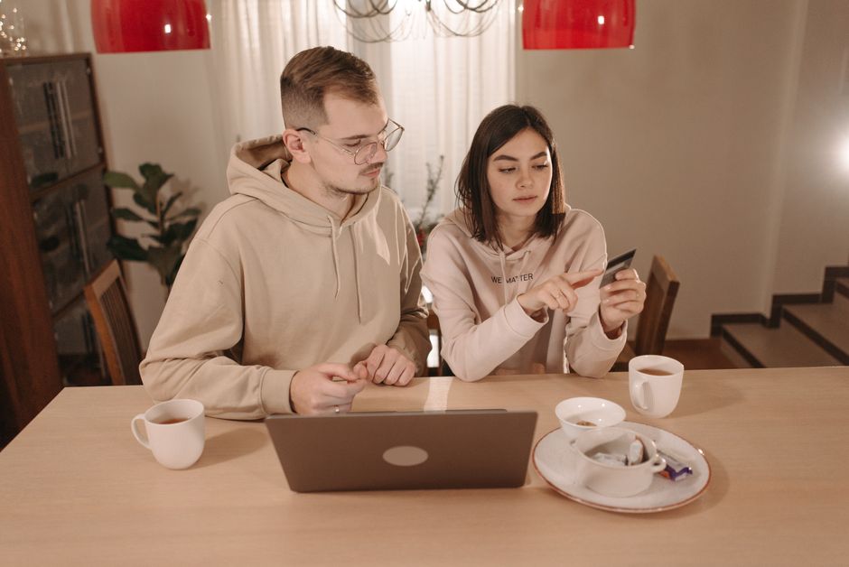 A couple enjoying online shopping with a laptop and credit card at home. Cozy indoor setting.